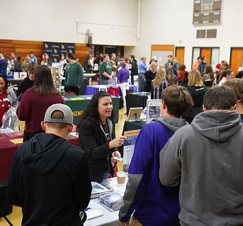 Students and representatives at tables from colleges, universities, and military in the Mid-State gym at a previous Education Fair.