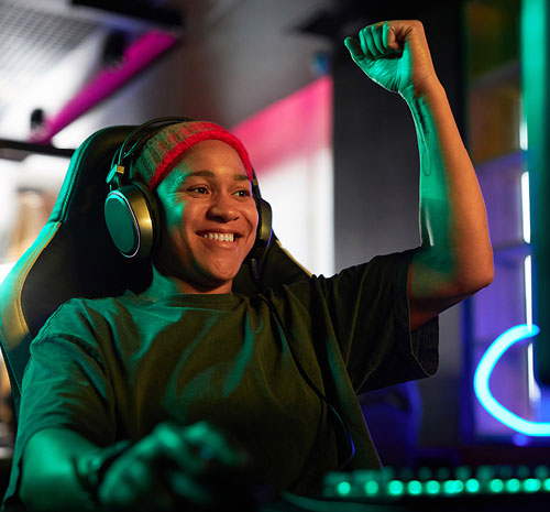 Person sitting in a computer chair with headphones on pumping their fist in the air