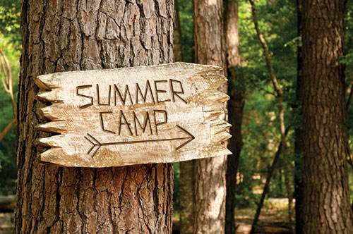 Wooden sign that reads "Summer Camp" hanging on a tree
