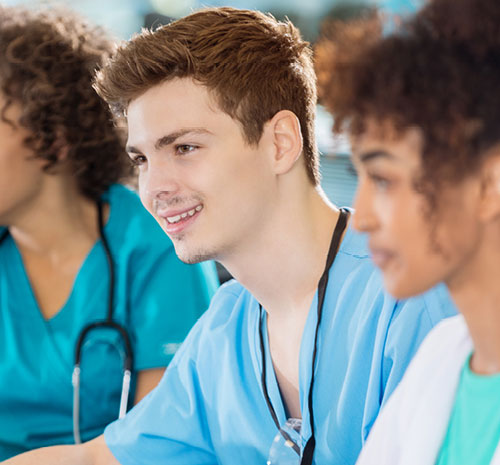 Several people in scrubs looking off to their right.