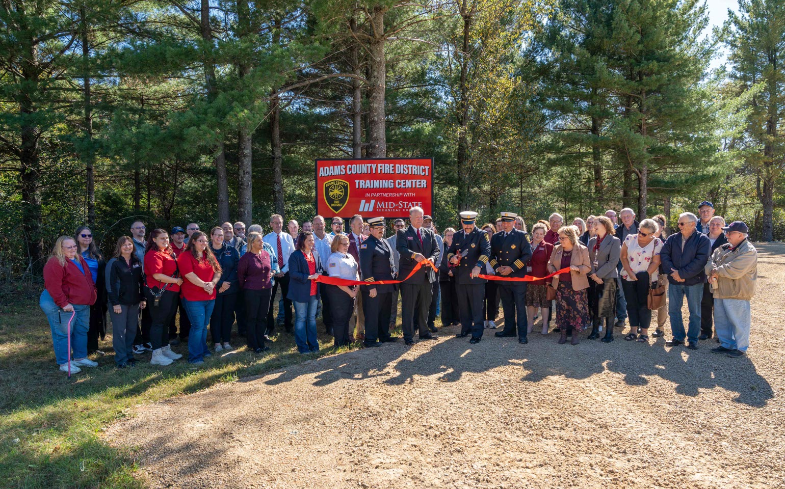 Mid-State Technical College staff and Adams County Fire District leadership look on while Rick Anderson, dean of Mid-State’s Adams Campus and School of Public Safety, helps Fire Chief Rodger Lauritzen of the Adams County Fire District cut the ribbon on the site of the Adams County Fire District Training Center in Adams, Oct. 8, 2025.