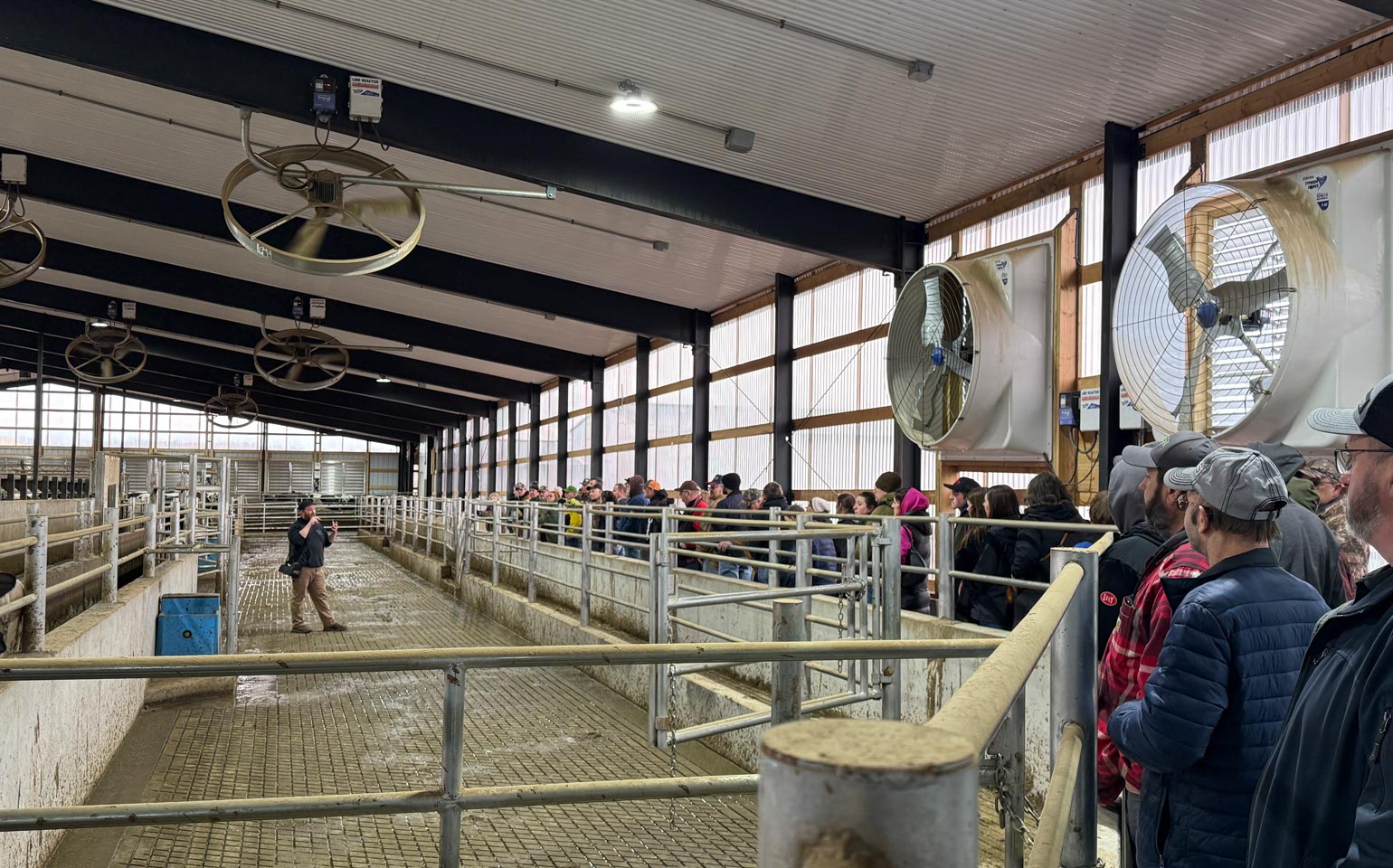 Farm Tour participants listen to a speaker inside a barn.