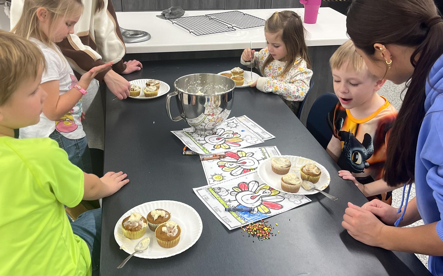 Student talks to young children eating at a table.