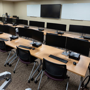 Training Room with multiple chairs at desks and tv mounted in front of room with a computer at a podium