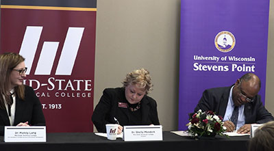 Dr. Shelly Mondeik, president of Mid-State Technical College, center, and Dr. Al S. Thompson, Jr., vice chancellor for student affairs and senior diversity officer at UW-Stevens Point, sign an agreement to provide housing for Mid-State students in a UW-Stevens Point residential living hall. The signing took place during an event formalizing the new partnership on Mid-State’s Stevens Point Campus, Feb. 4. Also pictured, left, is Dr. Mandy Lang, Mid-State’s vice president of student services & enrollment management.