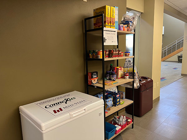 Stevens Point Food Pantry. Shelving with canned and boxed goods, and a mini freezer.