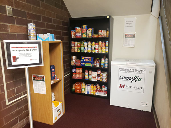 Wisconsin Rapids Food Pantry. Shelving with boxed and canned goods, and a mini freezer.