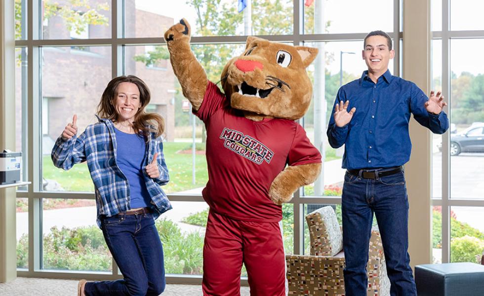 Two teenage students jumping alongside Mid-State Technical College cougar mascot, Grit.