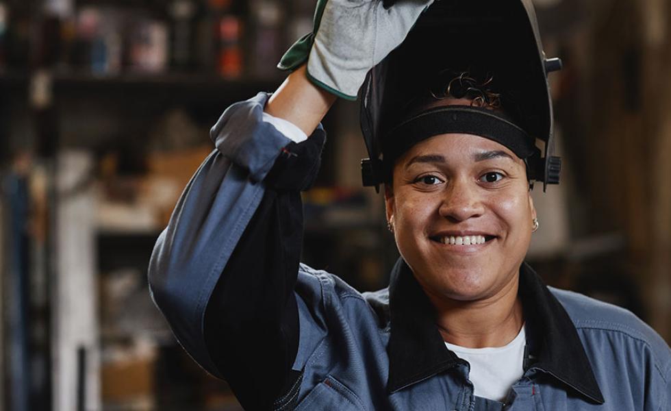 Woman welder lifting up welding helmet.