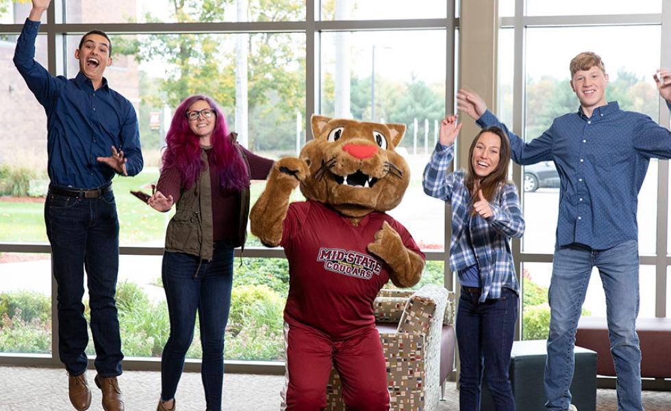 Mid-State students jumping with the mascot, Grit.