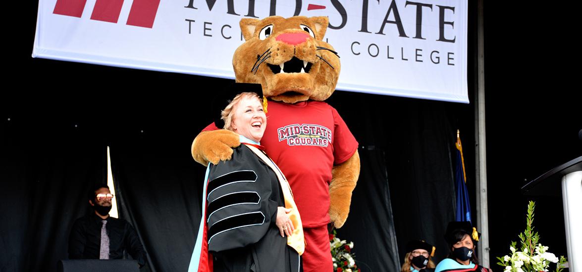 Mid-State Technical College President Dr. Shelly Mondeik with the College’s mascot Grit just after closing remarks to graduates at commencement on the Wisconsin Rapids Campus, May 16. Grit was unveiled for the first time at the event and served as a metaphor for the challenges students overcame in the last year as they worked to complete their degrees.