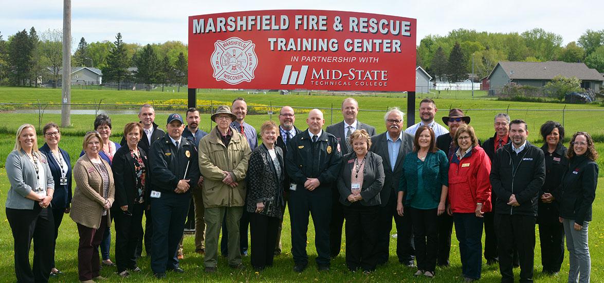 Supporters and partners gathered at the site of the Marshfield Fire & Rescue Center for the Marshfield Fire and Rescue Department and Mid-State Technical College partnership celebration, May 24. Front row, from left: Dr. Alex Lendved; Dr. Colleen Kane; Dr. Deb Stencil; Deputy Chief Everett Mueller; Commissioner Bill Penker; Mayor Lois TeStrake; Chief Peter Fletty; Dr. Shelly Mondeik; Sen. Kathleen Bernier; Rep. Donna Rozar; Craig Bernstein. Back row: Suzanne Rathe; Jill Steckbauer; Matt Schneider; Brandon