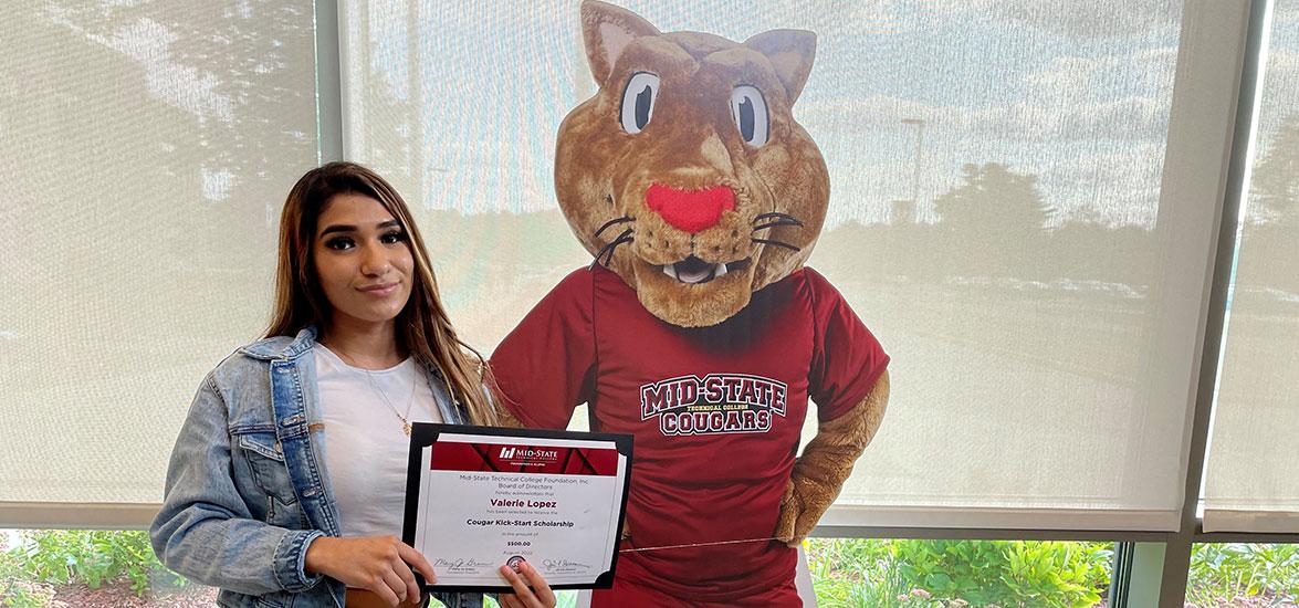 Cougar Kick-Start scholarship winner Valerie Lopez with a life-sized cutout of Mid-State’s “Grit” cougar mascot on the Wisconsin Rapids Campus, Aug. 19.