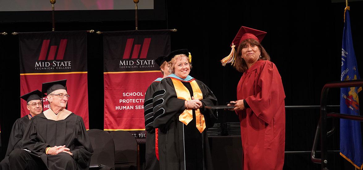 Katty Mansilla, HSED graduate, receives her diploma from Mid-State President Dr. Shelly Mondeik at the College’s commencement ceremony Dec. 10, 2022, on the Wisconsin Rapids Campus.