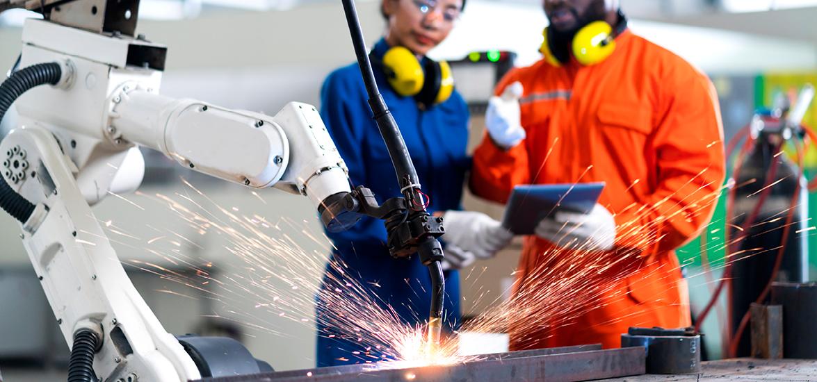 Two workers look on as metal fabrication machine works on a project.