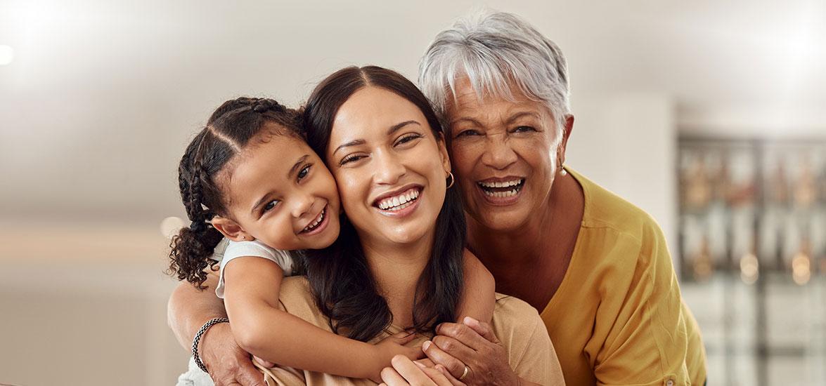 Grandmother, mother, and young daughter embrace.