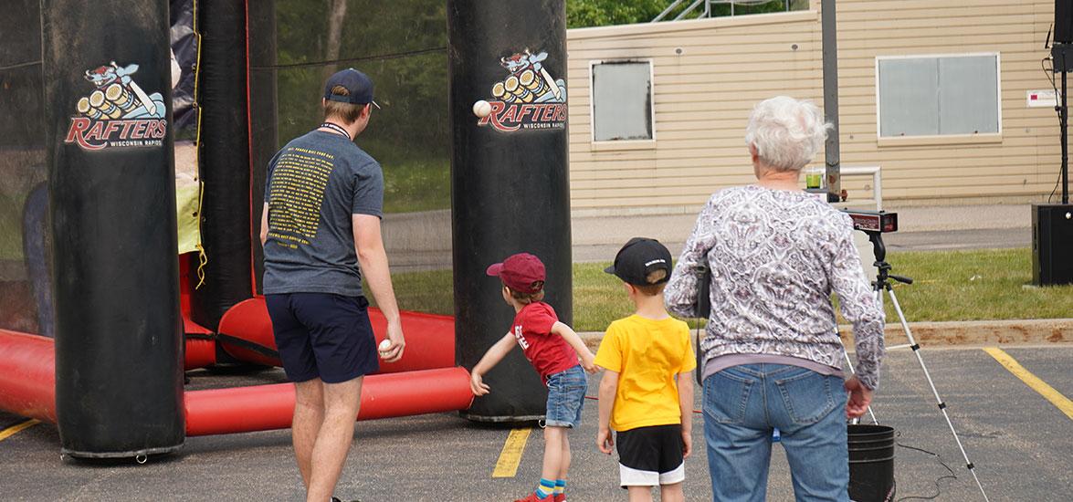 Rafters Meet-and-Greet & Cuts 4 Kids attendees see how fast they can throw a baseball in the fast pitch game at the 2023 event on the Wisconsin Rapids Campus.
