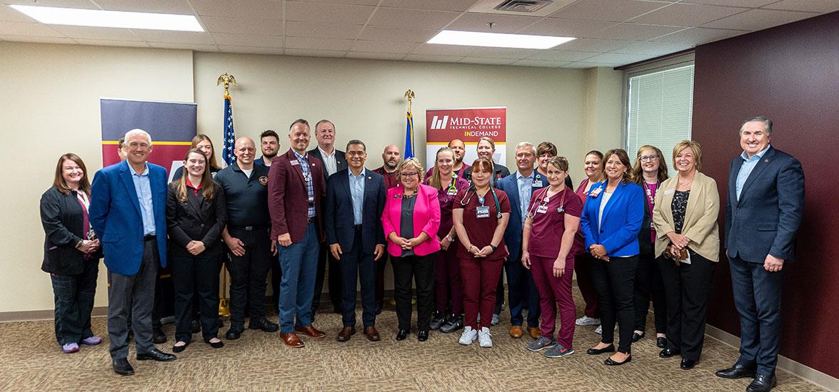 Mid-State Technical College’s president, Dr. Shelly Mondeik, front/center, with HHS Secretary Xavier Becerra, to her right, during the Secretary’s visit to the College’s Healthcare Simulation Center in Wisconsin Rapids, Wis., June 13. They are joined by Mid-State students, leadership and partners including leadership from Aspirus and Legacy Foundation of Central Wisconsin.