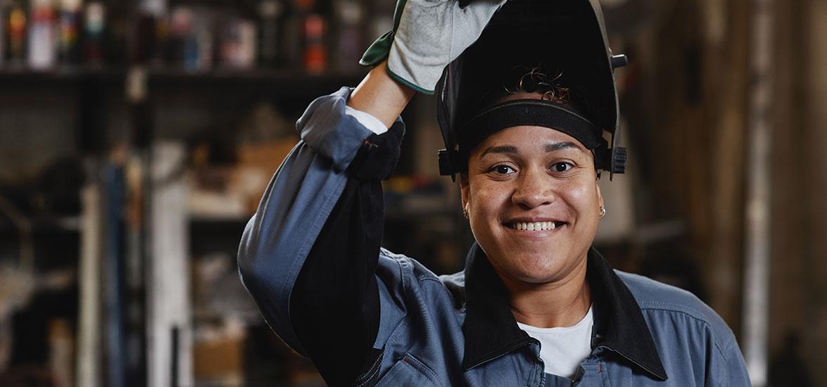 Woman welder lifting up welding helmet.