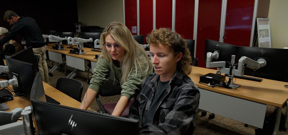 Natasha Janicki looks over the shoulder of her classmate as the two look at a computer screen.