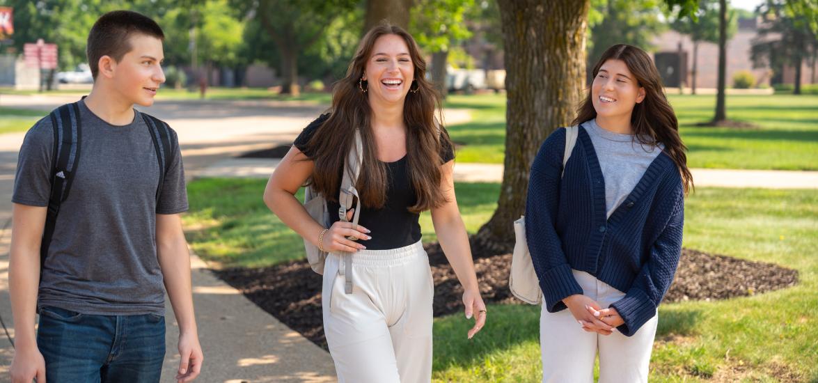 Three students with backpacks talk and laugh while walking together on Mid-State’s Wisconsin Rapids Campus.
