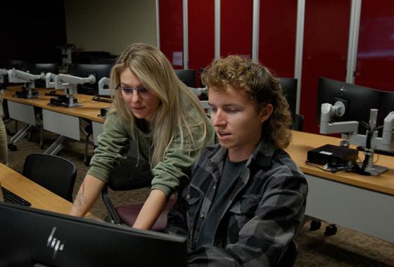 Natasha Janicki looks over the shoulder of her classmate as the two look at a computer screen.