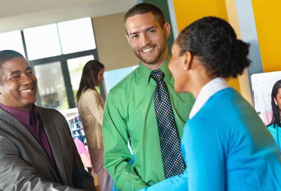 Three young adults shaking hands at a job fair.