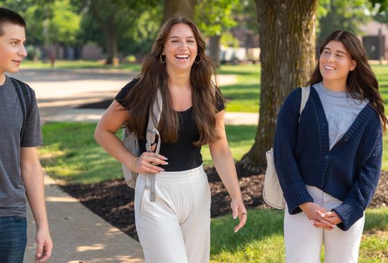 Three students with backpacks talk and laugh while walking together on Mid-State’s Wisconsin Rapids Campus.