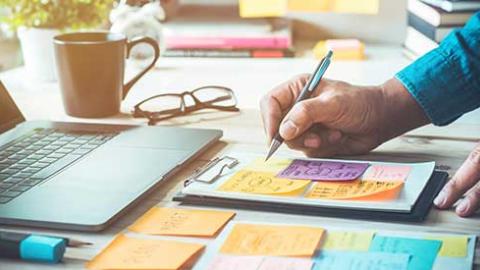 A person writing out marketing plans at a desk.